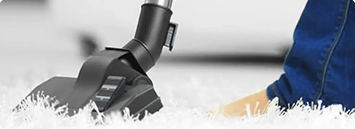 Close-up of a professional vacuuming a white carpet in Mustang.